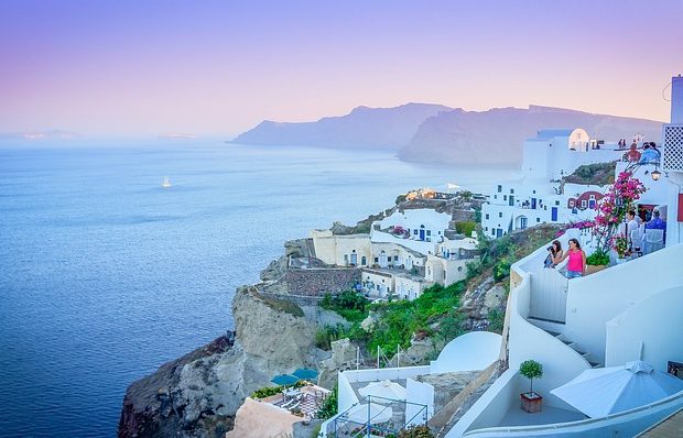 White houses in a pink purple sky over viewing a sea